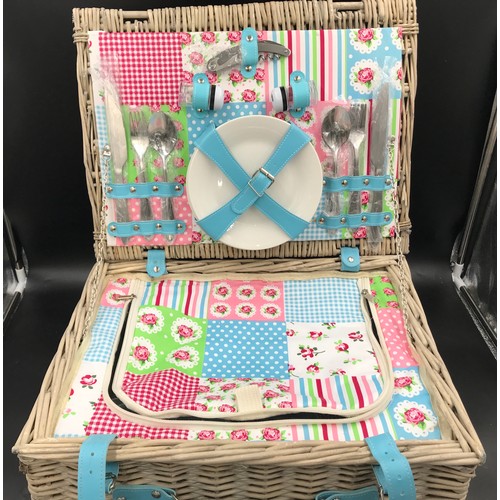 571 - A wicker picnic basket and contents set for four people. 45cms w x 35cms d x 21cms h.