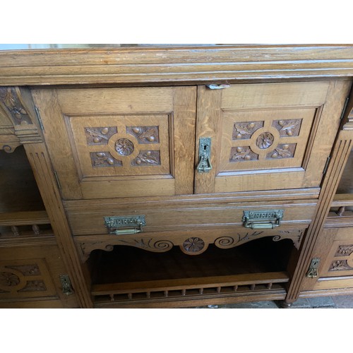 794 - An early 20thC oak Arts and Crafts sideboard. Three cupboards and three drawers with brass handles a... 