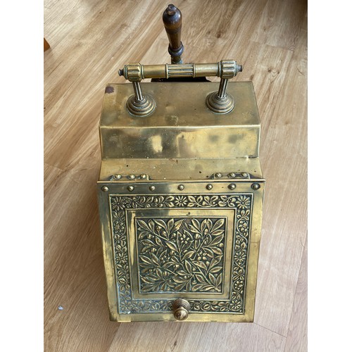 568A - A Victorian brass coal scuttle with floral design cover, raised on panelled feet with liner and shov... 