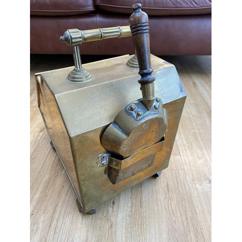 568A - A Victorian brass coal scuttle with floral design cover, raised on panelled feet with liner and shov... 