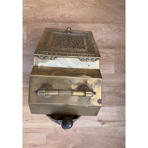 568A - A Victorian brass coal scuttle with floral design cover, raised on panelled feet with liner and shov... 