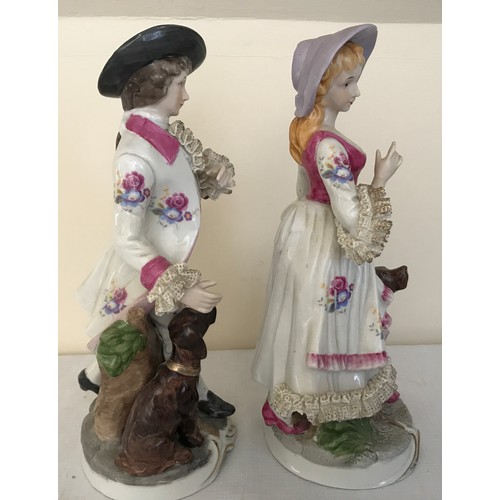 77a - A pair of Continental painted figurines of a man and woman both with dogs. 16cms h.