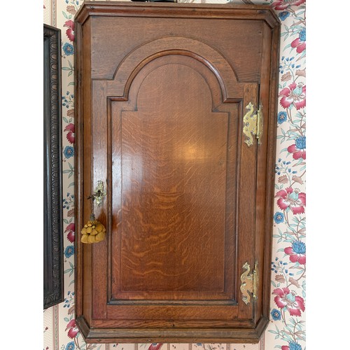 1230 - A 19thC oak corner cupboard with decorative brass hinges and escutcheon. 82cms h x 54cms w.