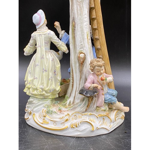 69 - A Meissen figurine group of apple pickers depicting a boy in a tree picking apples, a lady and gent ... 