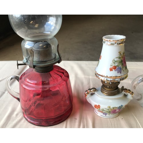 556 - Four oil lamps, one ruby glass, 29cms h including chimney, one yellow white glass floral pattern, an... 