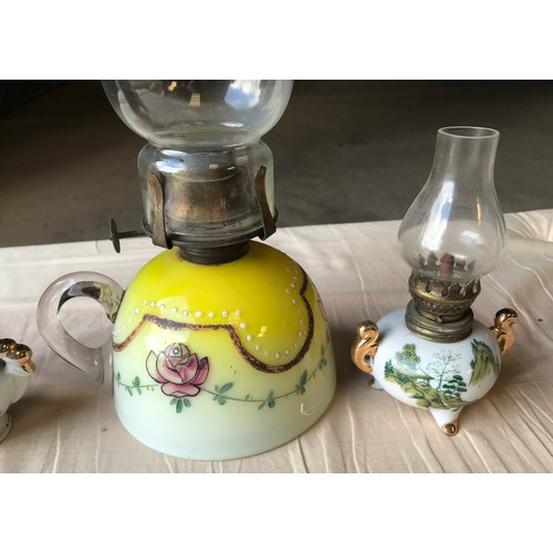 556 - Four oil lamps, one ruby glass, 29cms h including chimney, one yellow white glass floral pattern, an... 