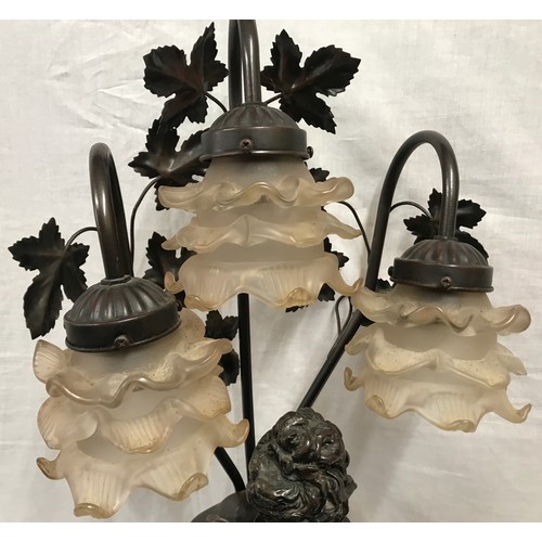 554 - A large bronze effect figural table lamp with 3 branch floral glass light shades. Approx. 82cms over... 