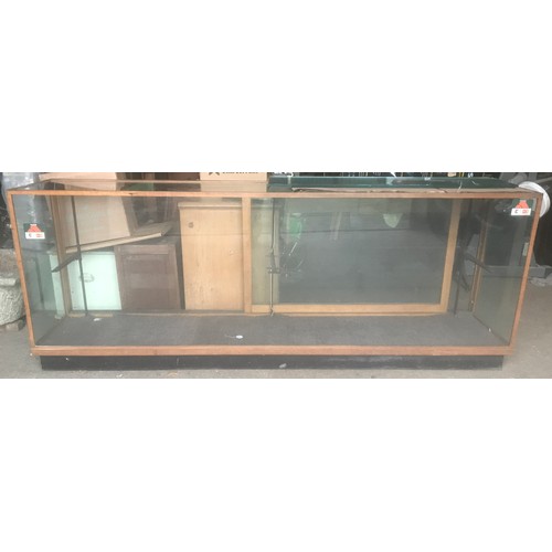 1286 - A large oak framed shop counter display cabinet, all sides glass, sliding doors with shelf bracket a... 