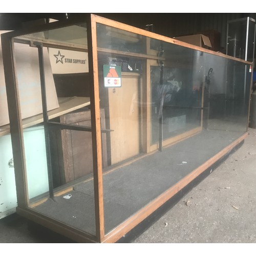 1286 - A large oak framed shop counter display cabinet, all sides glass, sliding doors with shelf bracket a... 