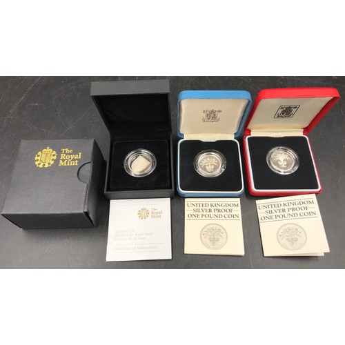 604 - Royal Mint silver proof coins : 2009 UK Shield of the Royal Arms £1 coin and two silver £1 coins, 19... 