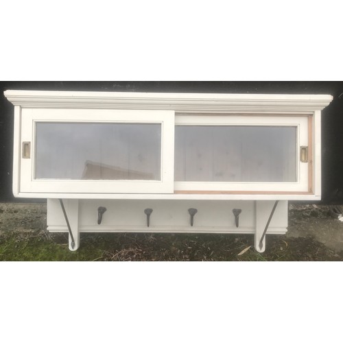 1291 - A painted pine wall mounted cabinet with sliding doors and iron hooks beneath. 126cms w x 42cms d x ... 