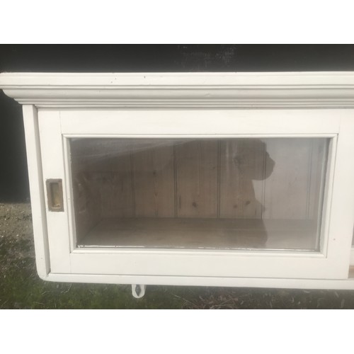 1291 - A painted pine wall mounted cabinet with sliding doors and iron hooks beneath. 126cms w x 42cms d x ... 