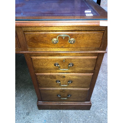 1263 - A mahogany kneehole desk with leather and glass top. 152 w x 90 x 77cm h.