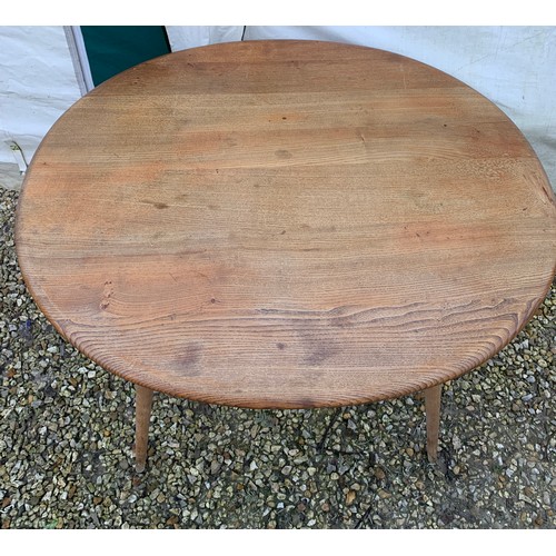 1265 - An Ercol oval topped dining table with under rack shelf and blue label. Top 99 x 89 x 73cm h