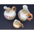 Three Royal Worcester blush ivory jugs with beak spouts and C scroll strap handles decorated with fl... 