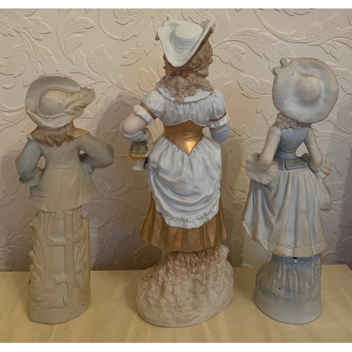 55 - A pair of continental bisque figurines and a single figurine of a girl reading.