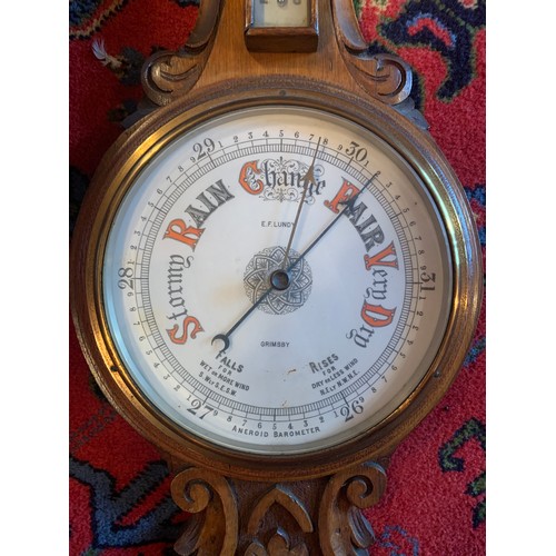 647 - A finely carved light oak aneroid barometer. E. F. Lundy, Grimsby. 87cm h.