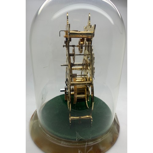 664 - A modern skeleton clock No. 245/1000 by Thwaites & Reed Ltd under a glass dome on a green onyx base.... 