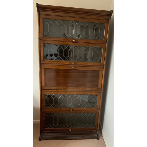 1144 - A 5 section mahogany and leaded glass modular bookcase with desk to centre. Glass doors slide up and... 