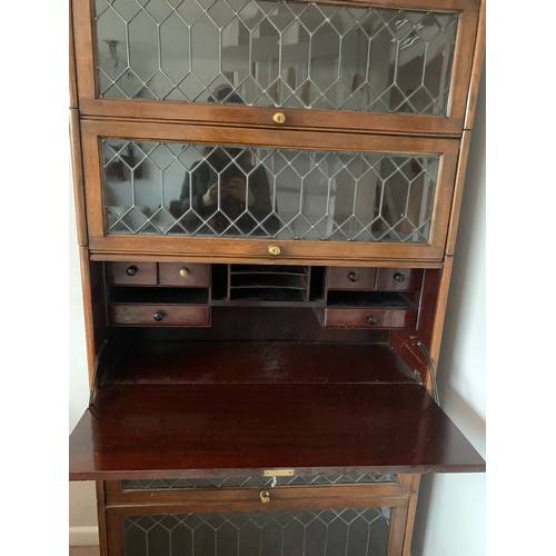 1144 - A 5 section mahogany and leaded glass modular bookcase with desk to centre. Glass doors slide up and... 