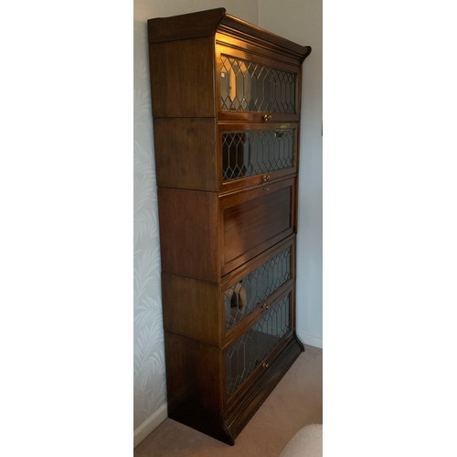 1144 - A 5 section mahogany and leaded glass modular bookcase with desk to centre. Glass doors slide up and... 