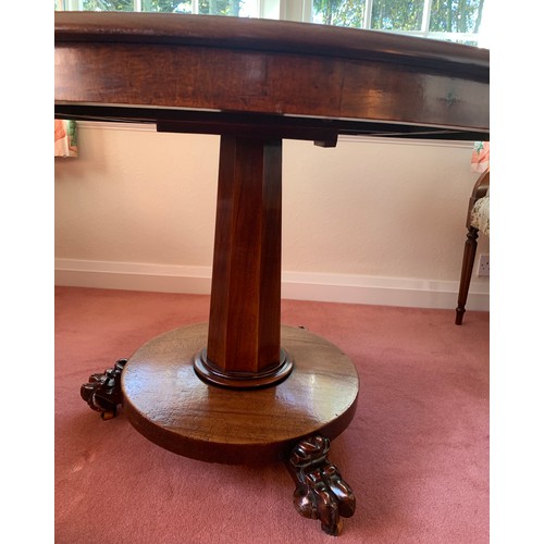 1155 - A 19thC mahogany circular tip-top centre table on paw feet. One metre d.