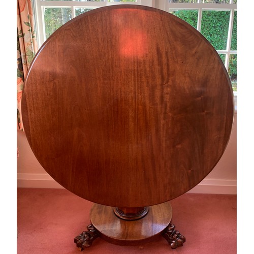 1155 - A 19thC mahogany circular tip-top centre table on paw feet. One metre d.