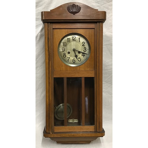 662 - A 1930's oak wall clock with pendulum and key.