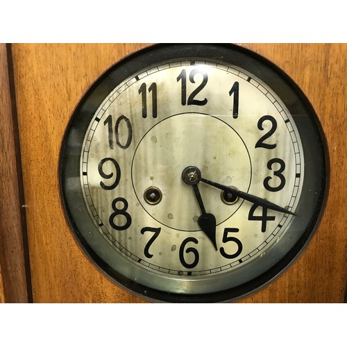 662 - A 1930's oak wall clock with pendulum and key.