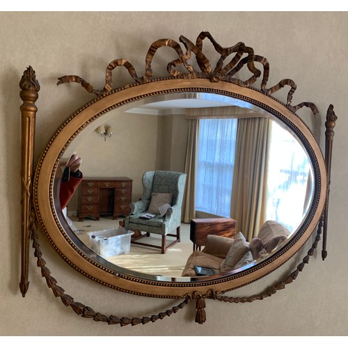 1350 - A gilt framed oval mirror with garland and bow decoration. 75 x 87cm.