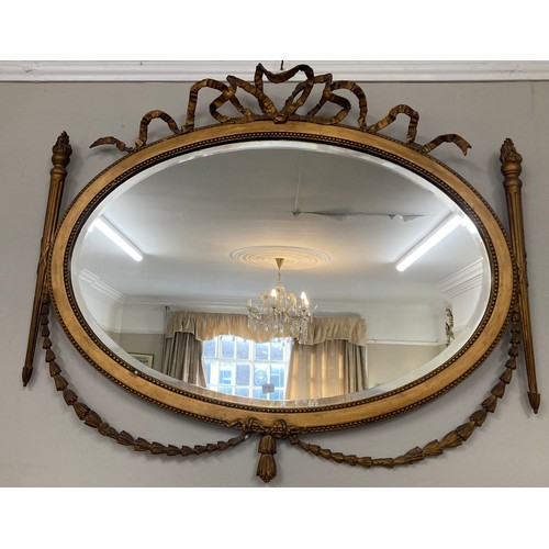 1350 - A gilt framed oval mirror with garland and bow decoration. 75 x 87cm.