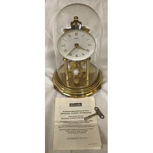 800 - A Kundo German brass dome glass cased anniversary clock with key, roman numerals, 400 day.