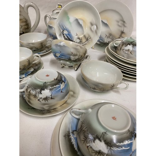 93 - A vintage Japanese part tea service decorated landscape with storks.  12 cups and saucers, tea pots,... 