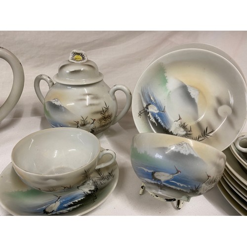 93 - A vintage Japanese part tea service decorated landscape with storks.  12 cups and saucers, tea pots,... 