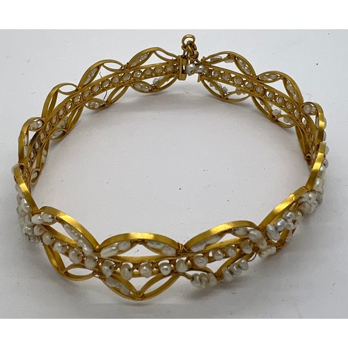 373 - A yellow metal bangle with seed pearl decoration. Tests as 22ct gold. 19gm total weight.