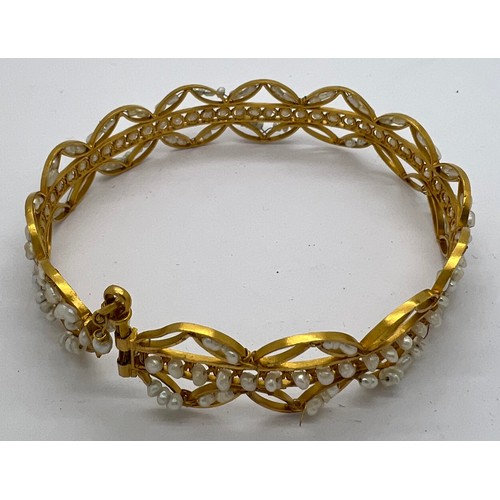 373 - A yellow metal bangle with seed pearl decoration. Tests as 22ct gold. 19gm total weight.