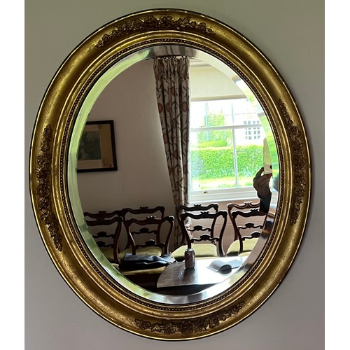 1357 - An oval gilt framed wall mirror with bevel edged glass. 68 h x 58cm w.