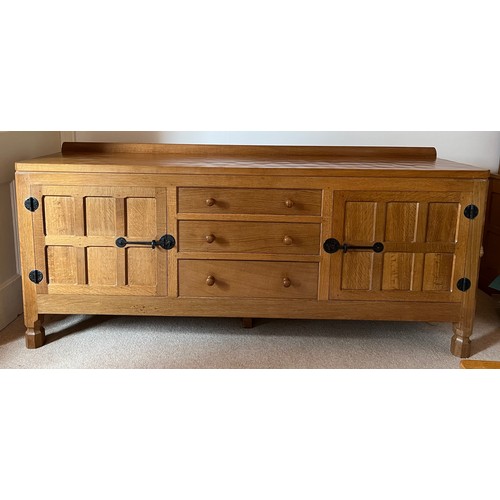 A Robert 'Mouseman' Thompson sideboard with adzed top comprising two cupboards with 3 central drawers, fitting cutlery draw to top. Bought 1977. 183 l x 46 d x 77cm h.