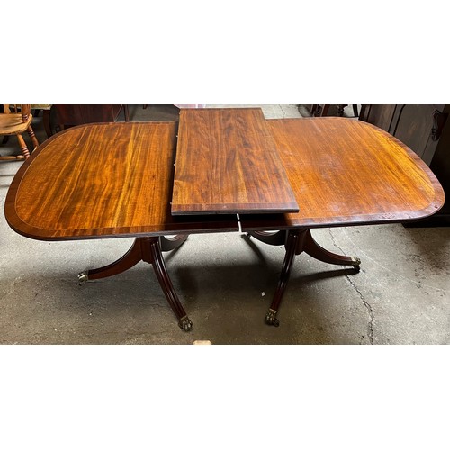 1324 - A 20thC mahogany twin pedestal dining table with extra leaf. Brass paw feet on brass castors. 180 l ... 