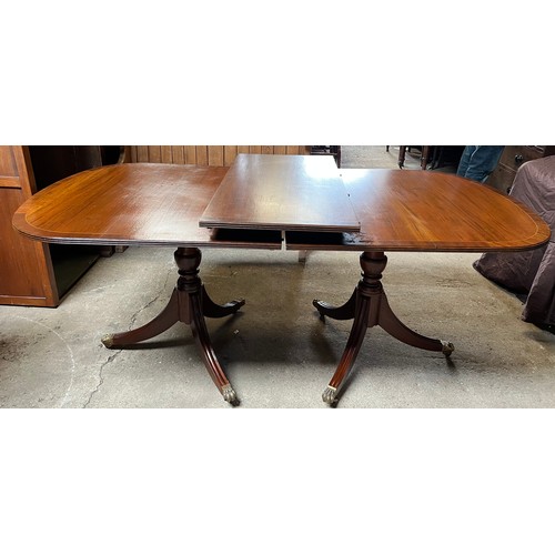 1324 - A 20thC mahogany twin pedestal dining table with extra leaf. Brass paw feet on brass castors. 180 l ... 