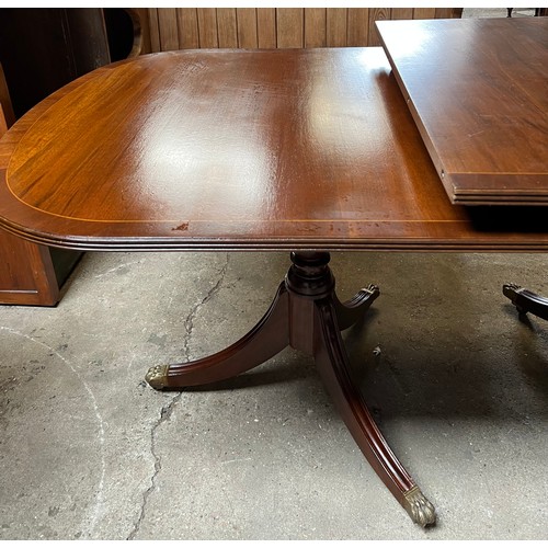 1324 - A 20thC mahogany twin pedestal dining table with extra leaf. Brass paw feet on brass castors. 180 l ... 