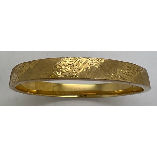 390 - A 9ct gold hinged bangle with engraved decoration. 18gm.