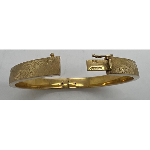 390 - A 9ct gold hinged bangle with engraved decoration. 18gm.