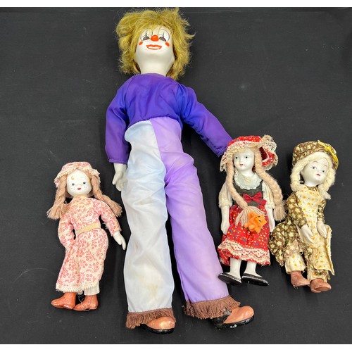 665A - Four bisque headed dolls including a wind up musical clown 50cm h.