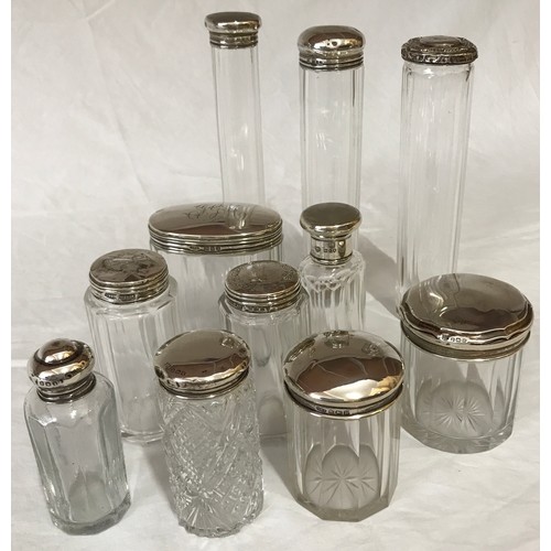 864 - Selection of silver topped glass containers some bearing a cartouche/pattern. Tallest 18cm (7).