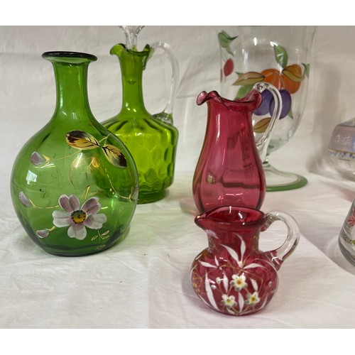 476 - A selection of coloured and hand painted glass ware to include: 3 x cranberry jugs, 3 x green jugs a... 