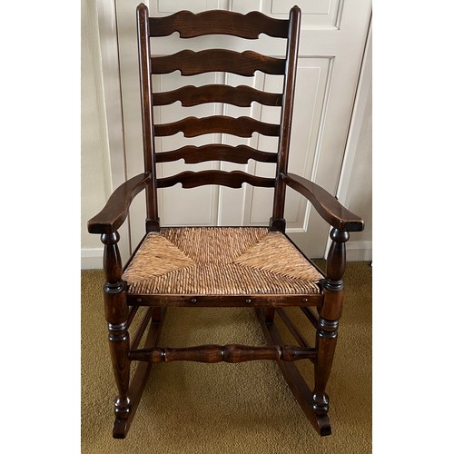 150 - Oak ladder backed rocking chair with rush seat.