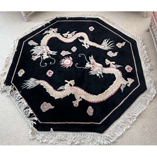 1123 - A black ground wool rug with dragon decoration. 157 x 157cm.