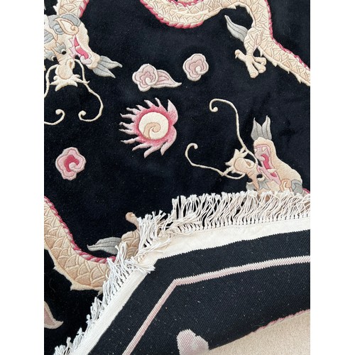 1123 - A black ground wool rug with dragon decoration. 157 x 157cm.