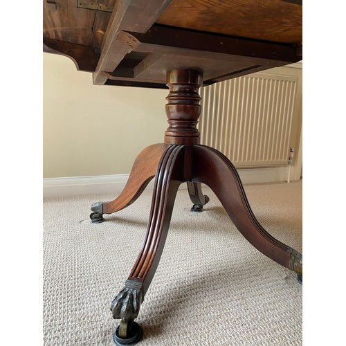 196 - A 19thC mahogany breakfast/dining table on centre turned support with brass lions paw feet and casto... 